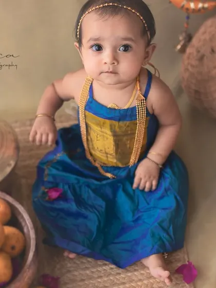 A full view of the sitter session with a traditional Indian theme. The baby is styled in a lovely dhoti-style outfit, sitting confidently among the props.
