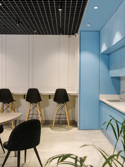 Adjacent to the main cafeteria is a pantry area with a pop of refreshing blue cabinetry, providing a visual contrast and a vibrant zone for coffee breaks.