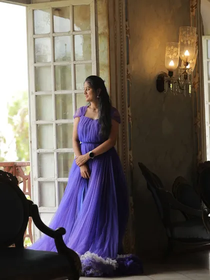 A beautiful solo portrait of the bride-to-be. The soft light from the window highlights the delicate details of the purple ruffled gown.