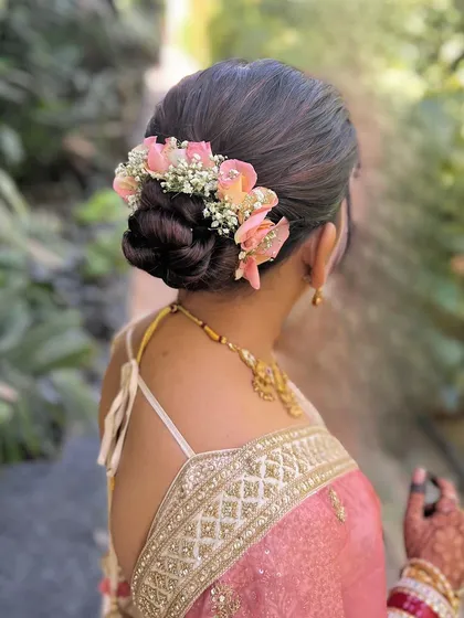 A close-up of a romantic bun with pink roses and baby's breath. This is a beautiful and delicate hairstyle for any special occasion.