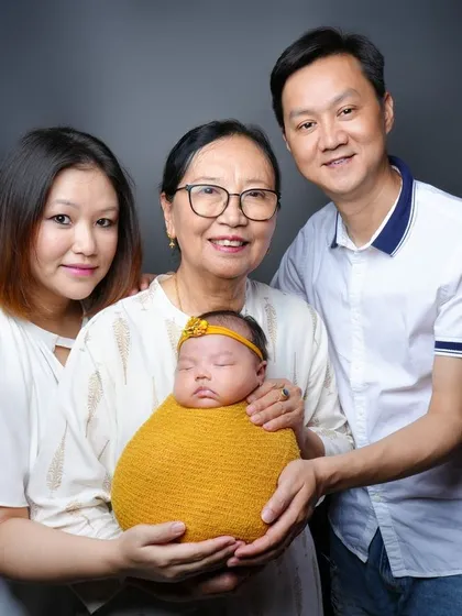 Welcoming the newest member with multiple generations. This portrait includes the baby's grandmother, creating a precious multi-generational family memory.