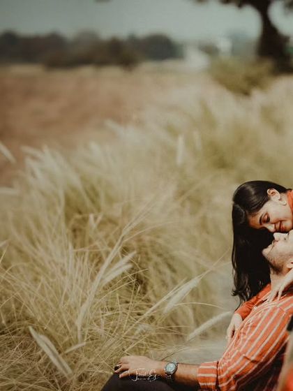 An intimate and rustic pre-wedding photo next to a car on a country road. The tall grass and warm tones give this shot a romantic, road-trip feel.
