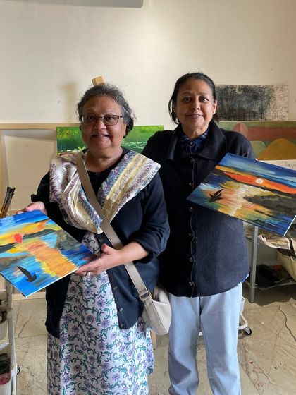 Two friends are all smiles after finishing their sunset seascape paintings. A perfect way to spend an afternoon.