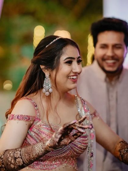 A candid shot of the bride dancing, her henna-covered hands in motion.