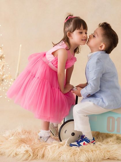 A sweet moment as a sister gives her brother a kiss on the cheek. A perfect capture of innocent sibling affection.