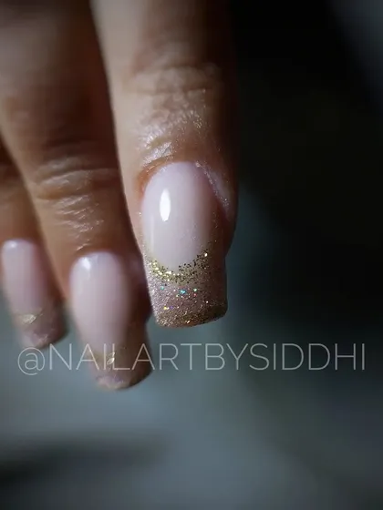 A simple and chic French manicure with a sparkling gold glitter tip.