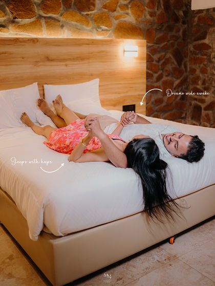 She escapes with hope, he dreams wide awake. This cozy shot on the bed captures their shared dreams and the comfort they find in each other's presence.