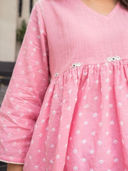 A close-up of the details on our Suhani Bandhej top. The delicate mirror work at the empire line adds a subtle sparkle to the hand-tied patterns, showcasing the thoughtful craftsmanship in every piece.