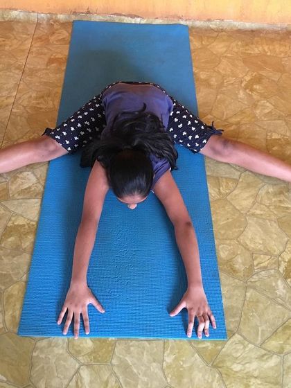 A young student in Upavistha Konasana, a seated wide-angled forward bend that calms the brain and stretches the backs of the legs.