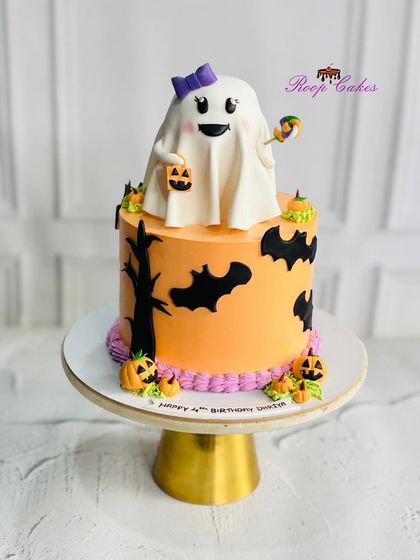A boo-tiful Halloween-themed cake for a 4th birthday. This fun and spooky cake features a cute ghost topper, bats, and jack-o'-lanterns, mixing adorable with just a little bit of eerie.
