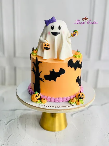 A boo-tiful Halloween-themed cake for a 4th birthday. It features a cute ghost topper, jack-o'-lanterns, and spooky bats.
