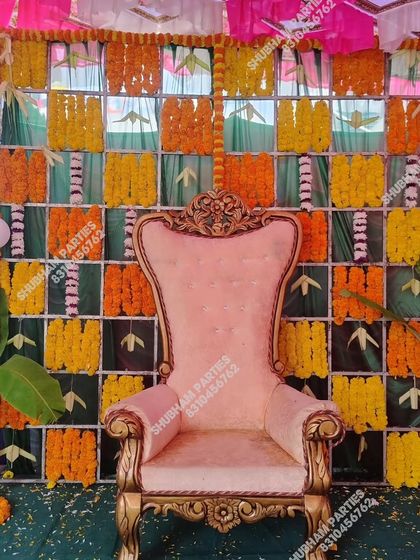 A traditional backdrop for a baby ceremony, made with a grid of banana leaves and marigold flowers, complete with a special chair for the mother-to-be.