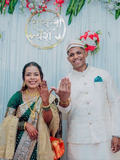 The moment it becomes official. The happy couple proudly shows off their new engagement rings, dressed in beautiful Maharashtrian attire under a custom sign with their names, "Sayali" and "Yash".
