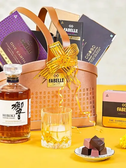 A luxurious Diwali hamper featuring a bottle of Hibiki Japanese whisky and Fabelle chocolates. The bright yellow background and elegant styling position this as a premium festive gift.