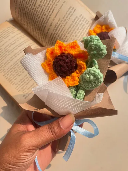 A close-up of the mini sunflower bouquet, held in hand to show its delicate size.
