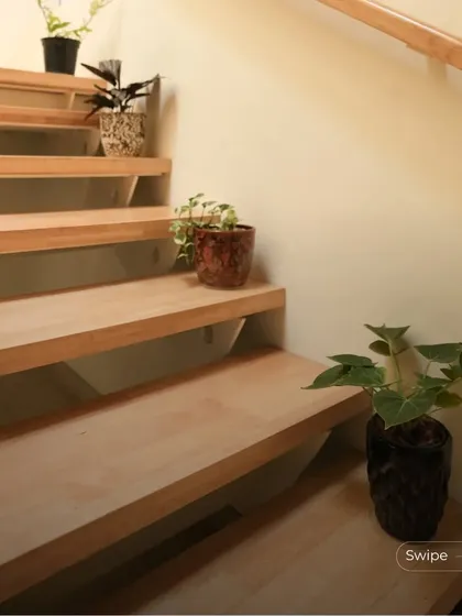 Small potted plants are placed on the steps of the staircase, adding a touch of green and life to the simple, elegant design.