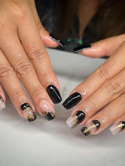 A striking design with black and gold foil. These square-shaped nails have a mix of solid black and a nude base with abstract gold flakes.