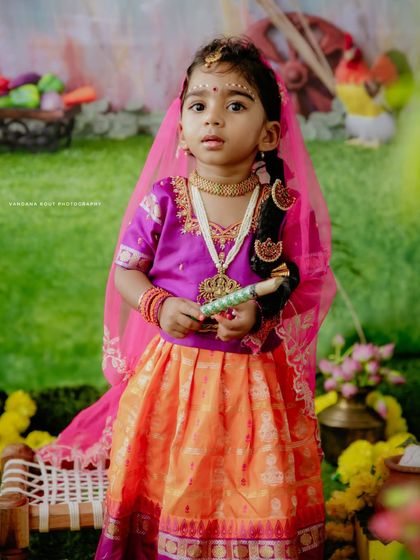 A full-length portrait of the little girl in her Janmashtami attire. The detailed costume and traditional props create an authentic and beautiful festive photograph.