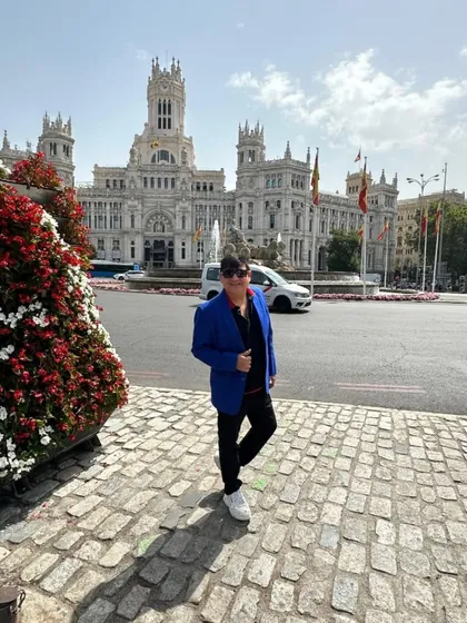 A full shot showing the combination of the blue blazer, black trousers, and the stunning architecture of the Cybele Palace.
