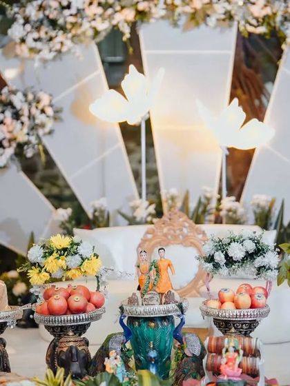 A centerpiece with dolls, surrounded by offerings and illuminated butterfly props.