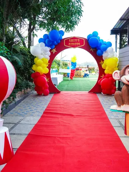 A circus-themed entrance with a red carpet, balloon arch, and a friendly monkey prop to greet guests.