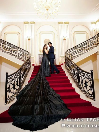 A classic pose on a grand staircase, with the bride's long black trail gown creating a beautiful line down the red carpet.
