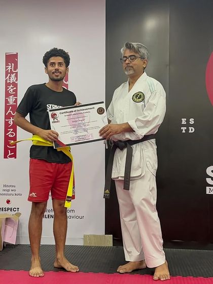 A student is awarded "Best Student" for his exceptional performance and growth, receiving his certificate from a senior instructor.