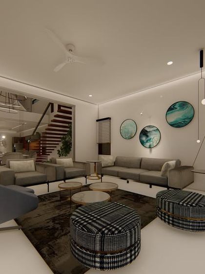 This open-plan living area features a modern grey sofa, patterned ottomans, and circular art pieces, creating a contemporary and relaxed feel. The design connects the living space with the dining area and staircase for a cohesive home experience.