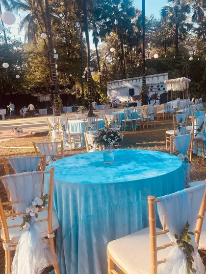 A beautiful blue-themed seating arrangement for a daytime event. The light blue velvet tablecloths and matching chair decor create a serene and elegant atmosphere.