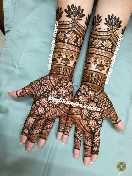 A clean, crisp shot of a full bridal mehndi with lotus and jhumka motifs. The symmetry and precision in this design make it a timeless choice for any bride.