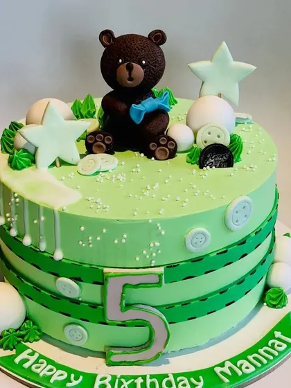 A charming teddy bear-themed cake for a 5th birthday. This green cake is decorated with button and stitch details, topped with a cute brown bear holding a candy.