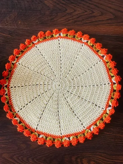 A clean, top-down shot of the cream and orange tulip doily.