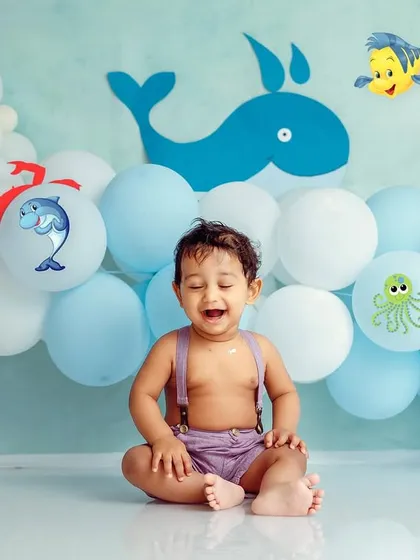 A big laugh before the cake gets completely smashed. The colorful balloons and sea creature decals create a cheerful atmosphere.