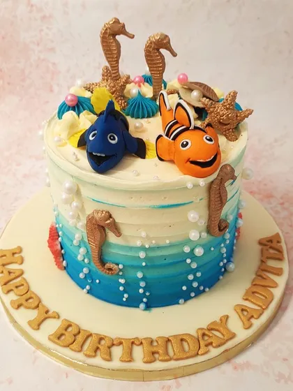 Our Nemo Dory Cake is an ocean dream, with an ombre buttercream effect, pearl-like bubbles, and golden seahorse details.