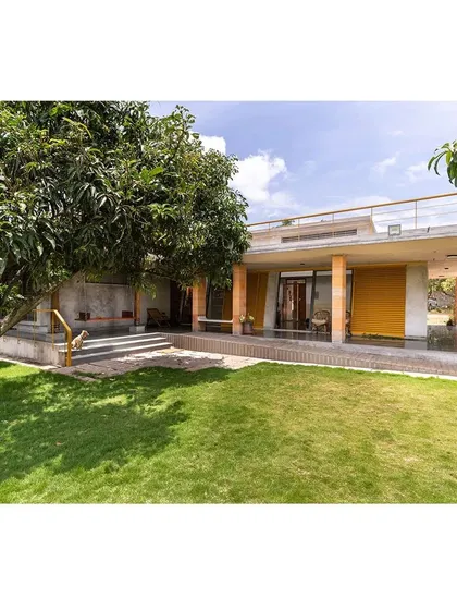 The house seen from the lawn, showing how the low-slung form sits gently in the landscape. The design uses simple rectangular forms to create an L-shaped structure that feels both modern and grounded.