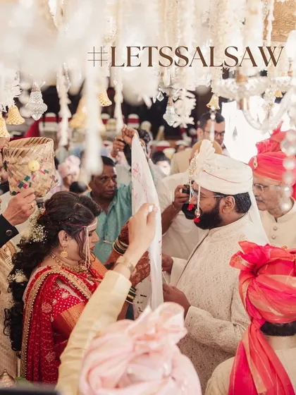 A moment from a traditional Maharashtrian wedding ceremony, where the 'antarpat' cloth is lowered. The decor is filled with beautiful hanging floral arrangements to sanctify the moment.