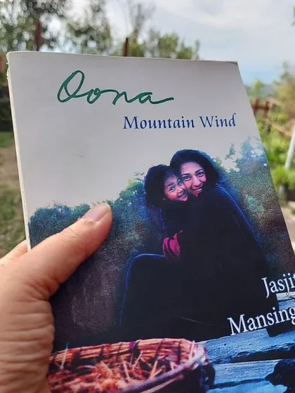 A participant holds a copy of 'Dona: Mountain Wind', a book that feels right at home in the Himalayas. Our library has a special section for mountain-themed literature.