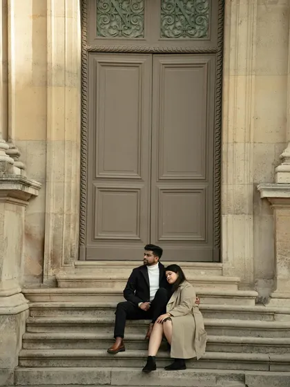 A moment of quiet reflection on the steps of a grand Parisian building. The classic architecture and the couple's elegant pose create a sophisticated and timeless pre-wedding portrait.