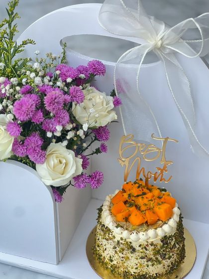 Our Mother's Day hamper, featuring a beautiful flower arrangement and a mini mango pistachio cake. It's the perfect way to spoil your mom.