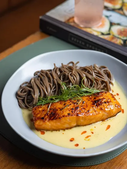 The chili miso glazed salmon presented with a cookbook in the background, hinting at the inspiration and craft behind our dishes.