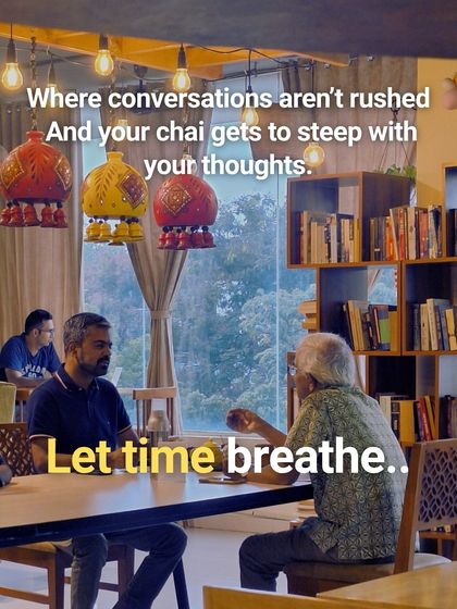 Here, conversations can unfold at their own pace. Two people enjoy a deep discussion over chai, surrounded by our library, where time seems to slow down just a little.