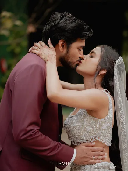A passionate kiss, capturing the romance of a modern love story. The groom's suit and bride's lehenga look stunning against our rustic-chic backdrops.
