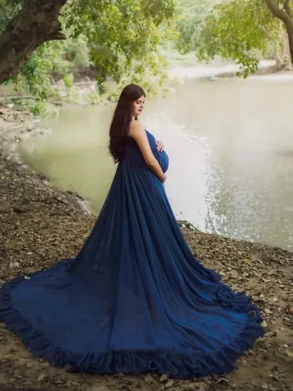 We can create stunning, dramatic portraits outdoors. This shot was taken by a serene riverside in Karnataka, with the long trail of the blue maternity gown adding a touch of magic to the natural landscape.