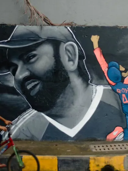 A tribute to Indian cricket captain Rohit Sharma on a public wall in Mumbai. This large-scale realistic portrait captures his likeness in monochrome, contrasted with a smaller, full-color action shot, celebrating a true sports icon.