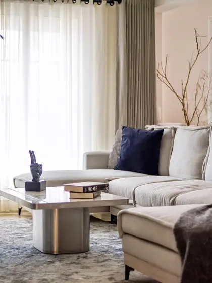 The combination of the soft boucle fabric, the cool marble, and the warm, natural light from the window creates a perfectly balanced and inviting living space.