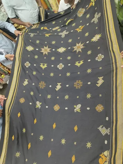 Students from a design school examining a black silk saree with elaborate Kasuti work. Sharing this knowledge with the next generation is essential for keeping the craft alive.
