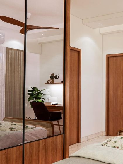 A bedroom with ethnic vibes, featuring a mirrored wardrobe that reflects the room's light and greenery from the balcony, making the space feel larger and more connected to the outdoors.