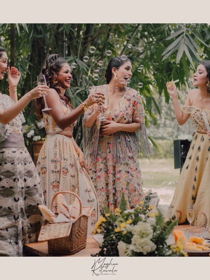 The bride and her bridesmaids enjoying a cheerful moment. Their coordinated floral dresses by Payal Singhal create a beautiful, unified look for this outdoor celebration.