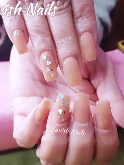 A sweet and simple set of sheer nude square nails with a single accent nail featuring tiny heart glitter.