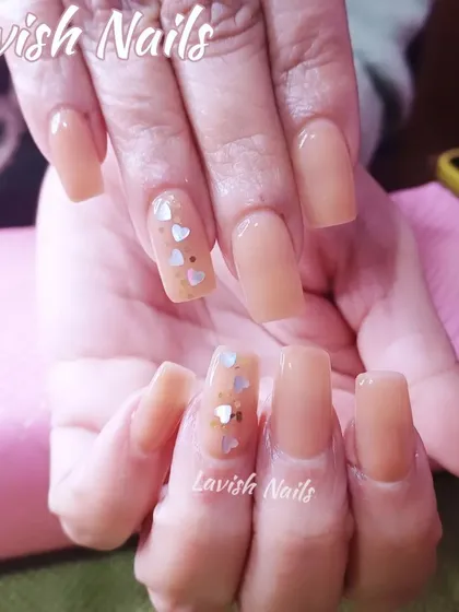 A sweet and simple set of sheer nude square nails with a single accent nail featuring tiny heart glitter.